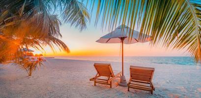 Panoramic tropical beach sunset rays, two sun beds, loungers, umbrella under palm tree. White sand, sea shore horizon, colorful twilight sky, calm relax banner. Inspirational beach resort hotel photo