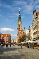 gdansk, polonia, 17 de abril de 2018, la gente camina por dluga long market street dlugi targ square en el antiguo centro histórico cerca del ayuntamiento con la torre del reloj, hermosos edificios típicos de casas coloridas