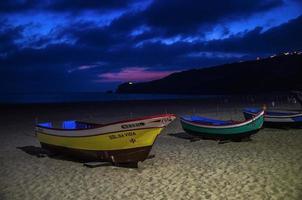 Nazare, Portugal - June 21, 2017 Traditional fishing boats on the sandy beach of Nazare at sunset dusk twilight, Portugal, Atlantic ocean