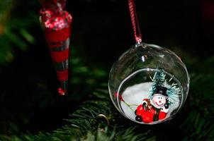 muñeco de nieve en bola en el árbol de navidad foto
