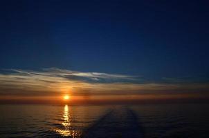 sunset on sea with trace of ship photo