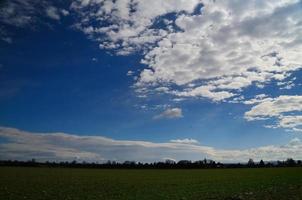 green field with white clouds photo