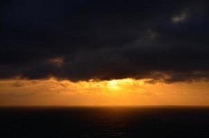 nubes oscuras y puesta de sol en el mar foto