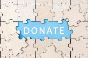 Donate word on blue background surrounded by puzzle pieces photo