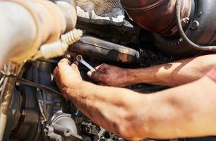 Combine machine service, mechanic repairing motor outdoors photo