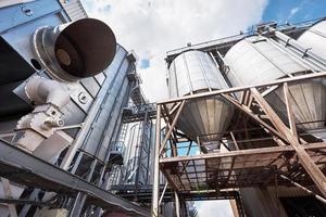 Agricultural Silos. Building Exterior. Storage and drying of grains, wheat, corn, soy, sunflower against the blue sky with white clouds photo