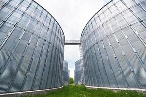 silos agrícolas. exterior del edificio almacenamiento y secado de granos, trigo, maíz, soja, girasol contra el cielo azul con nubes blancas foto