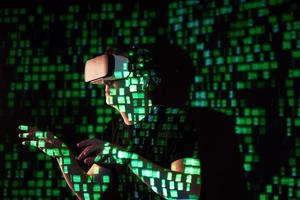 Double exposure of a caucasian man and Virtual reality headset is presumably a gamer or a hacker cracking the code into a secure network or server, with lines of code photo