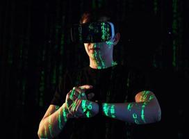 Double exposure of a caucasian man and Virtual reality headset is presumably a gamer or a hacker cracking the code into a secure network or server, with lines of code photo