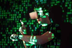 Double exposure of a caucasian man and Virtual reality headset is presumably a gamer or a hacker cracking the code into a secure network or server, with lines of code photo