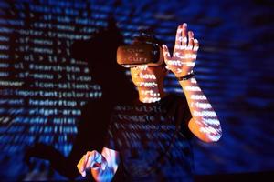 Double exposure of a caucasian man and Virtual reality headset is presumably a gamer or a hacker cracking the code into a secure network or server, with lines of code photo