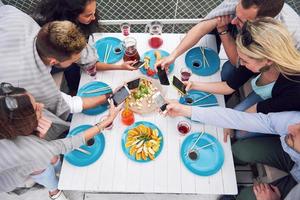 jóvenes amigos felices estaban sentados en una mesa y haciendo un picnic al aire libre foto