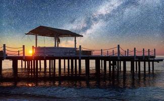 Beautiful view of wooden pier in the sea and starry sky and the Milky Way. photo