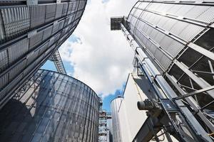 Agricultural Silos. Building Exterior. Storage and drying of grains, wheat, corn, soy, sunflower against the blue sky with white clouds photo