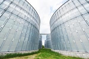 Agricultural Silos. Building Exterior. Storage and drying of grains, wheat, corn, soy, sunflower against the blue sky with white clouds photo