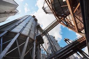 Agricultural Silos. Building Exterior. Storage and drying of grains, wheat, corn, soy, sunflower against the blue sky with white clouds photo