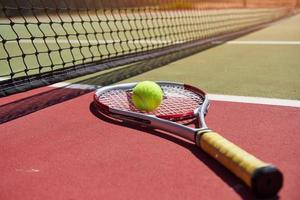 A tennis racket and new tennis ball on a freshly painted tennis court. photo