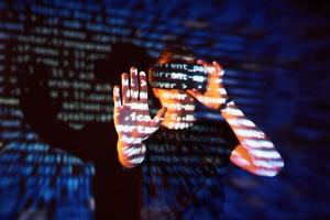 Double exposure of a caucasian man and Virtual reality headset is presumably a gamer or a hacker cracking the code into a secure network or server, with lines of code photo