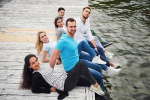 Group of beautiful young people on the pier, friends satisfaction creates emotional life photo