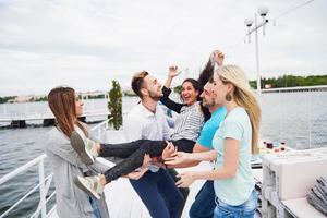 grupo de amigos felices en la playa, hombre lanzando a una mujer feliz. foto