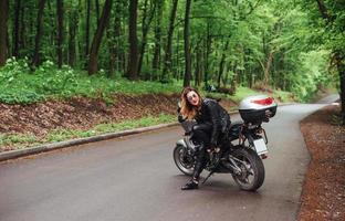 una atractiva chica sexy en una moto deportiva posando afuera foto