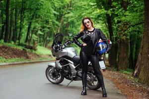 An attractive sexy girl on a sports motorbike posing outside photo