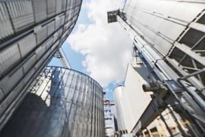 Agricultural Silos. Building Exterior. Storage and drying of grains, wheat, corn, soy, sunflower against the blue sky with white clouds photo