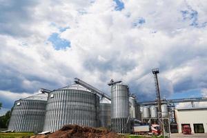 Agricultural Silos. Building Exterior. Storage and drying of grains, wheat, corn, soy, sunflower against the blue sky with white clouds photo