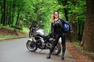 An attractive sexy girl on a sports motorbike posing outside photo