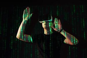 Double exposure of a caucasian man and Virtual reality headset is presumably a gamer or a hacker cracking the code into a secure network or server, with lines of code photo