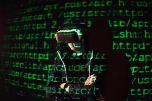 Double exposure of a caucasian man and Virtual reality headset is presumably a gamer or a hacker cracking the code into a secure network or server, with lines of code