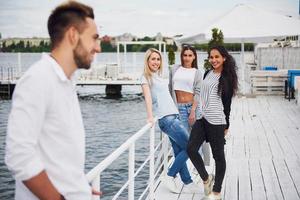 Portrait of a young and happy people at rest on the pier. Friends enjoying a game on the lake. Positive emotions. photo