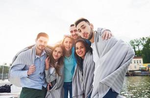 sonriente feliz grupo de amigos posando para la cámara al aire libre en el muelle de la playa foto