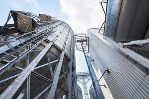 Agricultural Silos. Building Exterior. Storage and drying of grains, wheat, corn, soy, sunflower against the blue sky with white clouds photo