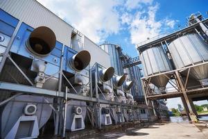 Agricultural Silos. Building Exterior. Storage and drying of grains, wheat, corn, soy, sunflower against the blue sky with white clouds photo