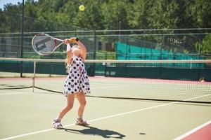 linda niña jugando tenis en la cancha de tenis afuera foto
