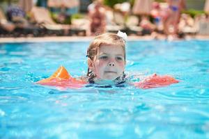 chica nadando en la piscina con brazaletes en un caluroso día de verano.