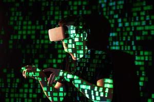 Double exposure of a caucasian man and Virtual reality headset is presumably a gamer or a hacker cracking the code into a secure network or server, with lines of code photo