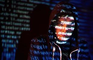 Cyber attack with unrecognizable hooded hacker using virtual reality, digital glitch effect photo