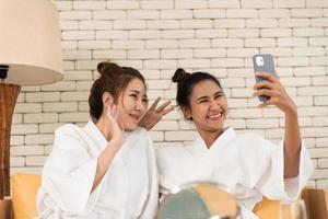 Two Asian female friends chat while waiting in the spa reception area photo