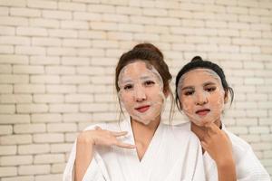 Two Asian female friends chat while waiting in the spa reception area photo