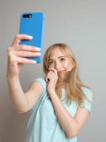 elegante hermosa mujer rubia blogger haciendo selfie con su teléfono inteligente. tendencia, tecnología, belleza, concepto de moda. foto