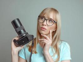 blonde stylish cheerful woman photographer in glasses and holding photo camera. Hobby, work, shooting concept