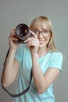 blonde stylish cheerful woman photographer in glasses and holding photo camera. Hobby, work, shooting concept