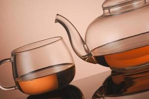 Transparent glass teapot and cup with tea photo