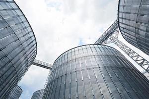 Agricultural Silos. Building Exterior. Storage and drying of grains, wheat, corn, soy, sunflower against the blue sky with white clouds photo