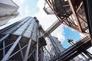 Agricultural Silos. Building Exterior. Storage and drying of grains, wheat, corn, soy, sunflower against the blue sky with white clouds photo