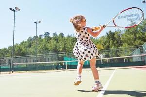 Happy little girl playing tennis photo