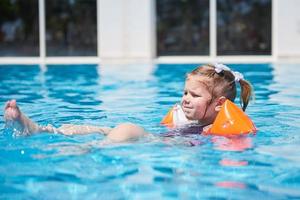 Girl swimming in the pool in armlets on a hot summer day. photo