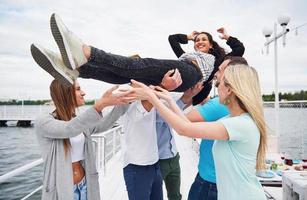 grupo de amigos felices en la playa, hombre lanzando a una mujer feliz. foto